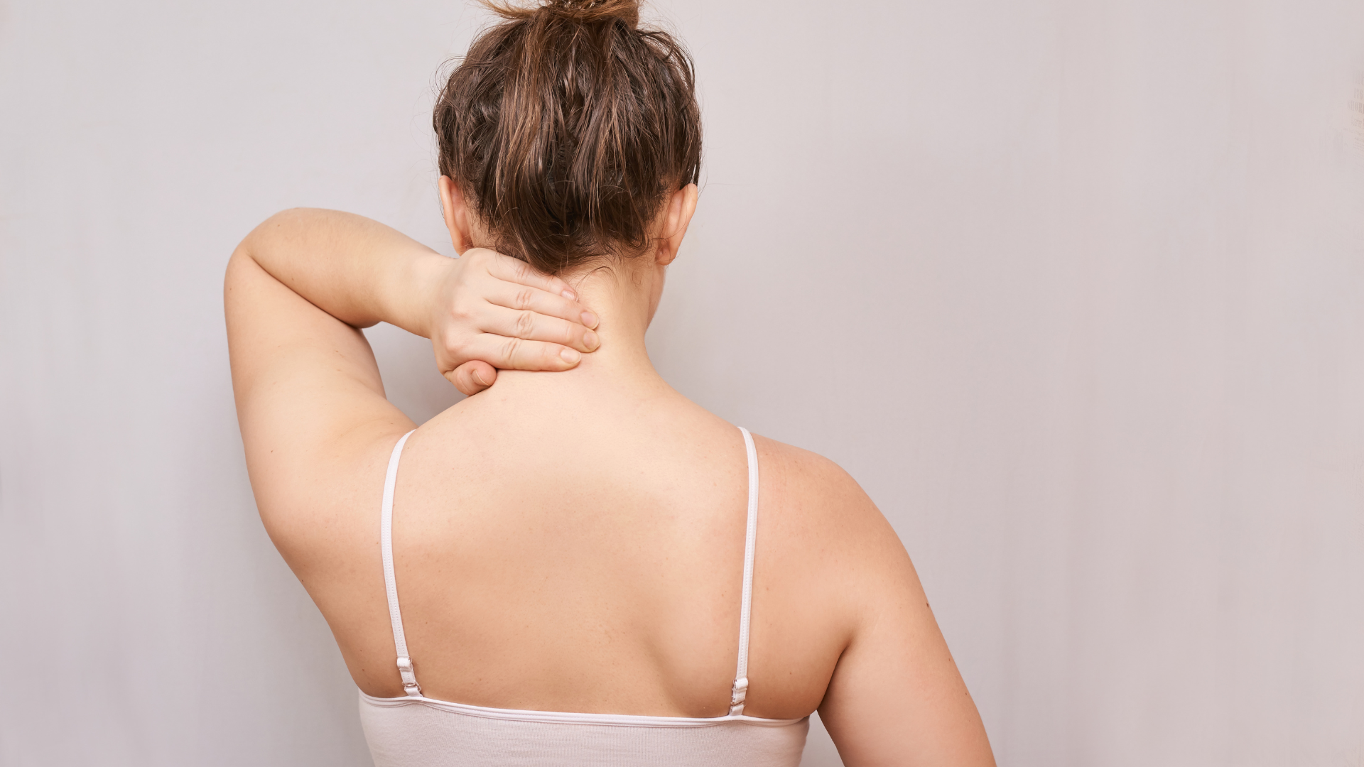 Woman touching upper back representing regenerative medicine for pain relief