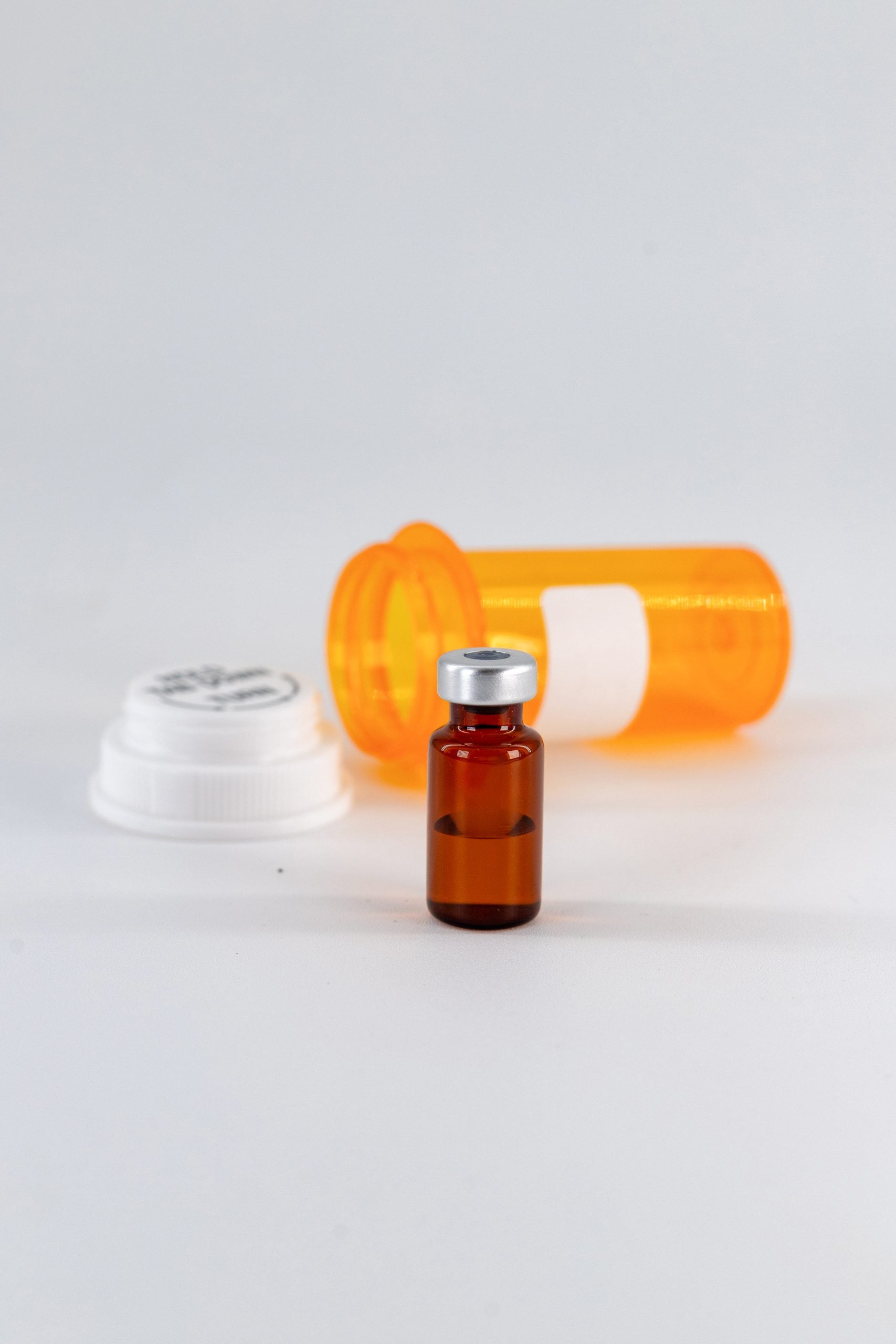 Peptide therapy vial beside an orange prescription bottle